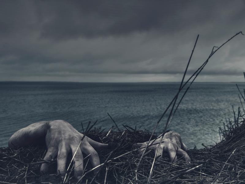 Mørk strand med zombie-hænder