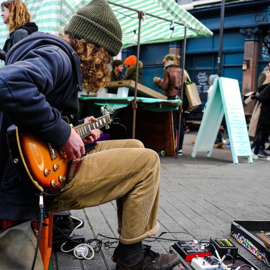 En unge mand spiller guitar på gaden